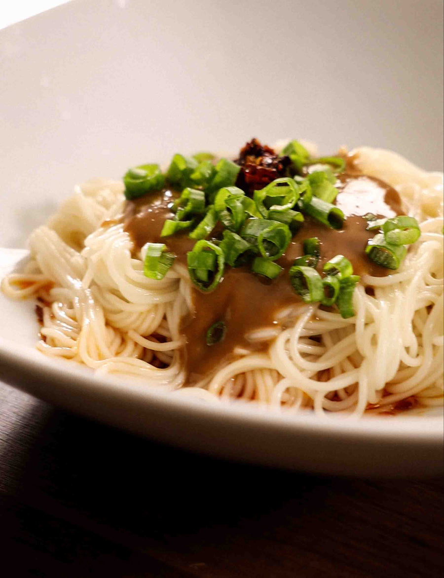 A bowl of Spicy Sesame Paste Noodles under dramatic lighting.
