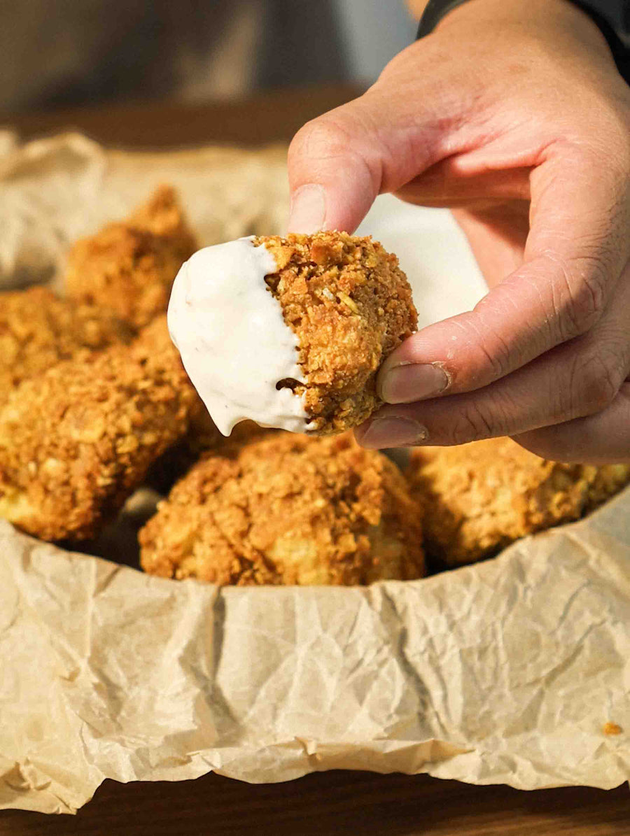A hand holding a crispy cauliflower bite dipped in ranch dip.