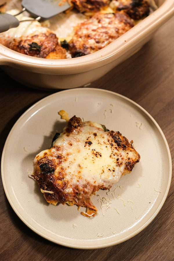 Golden-brown Chicken Parmesan topped with melted mozzarella and tomato sauce, served on a plate with fresh basil garnish.
