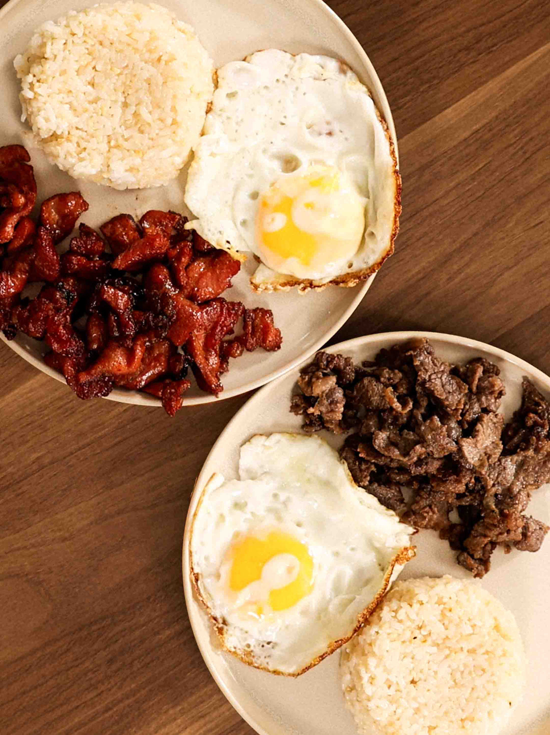 Two plates of delicious Tapsilog and Tocilog on a wooden table. 