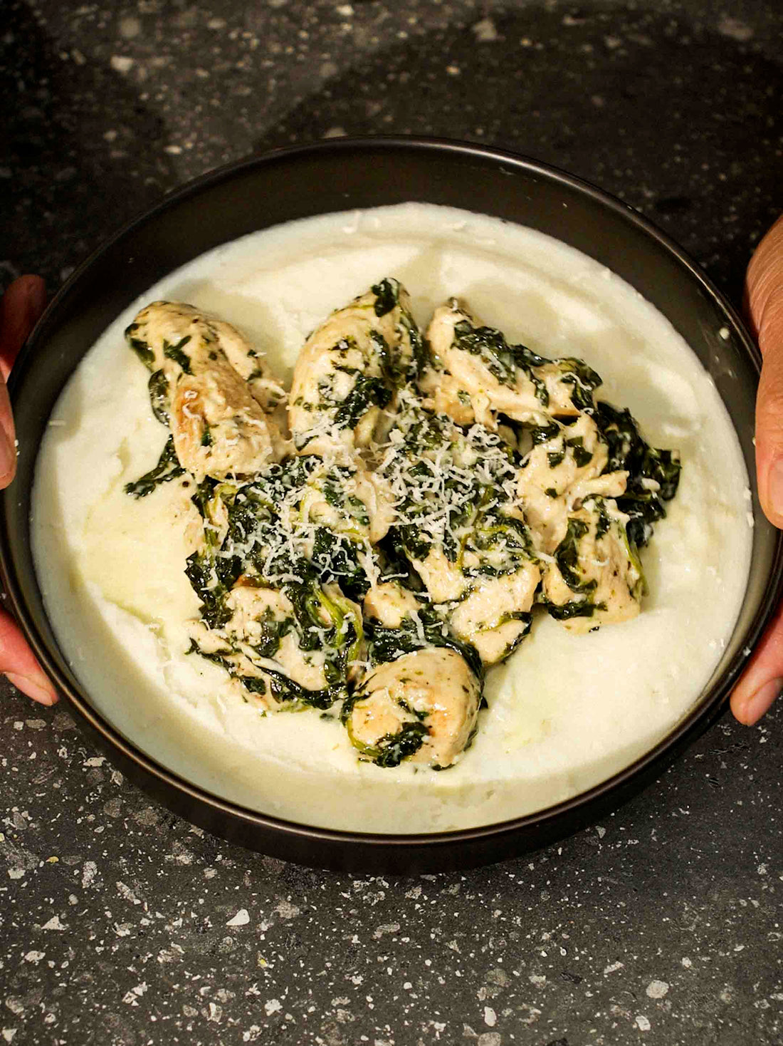 A bowl of Creamy Spinach Chicken on top of a spread of mash potatoes. Made using the Magnifique Round Claypot Multi-Cooker