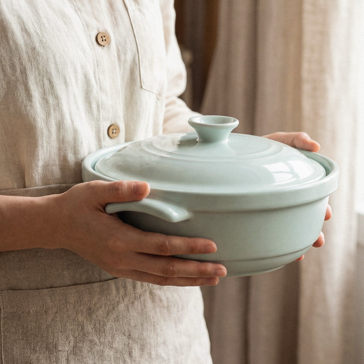 The Flami Pot, a non-toxic cookware, is held by a person showcasing its elegant design and functionality.