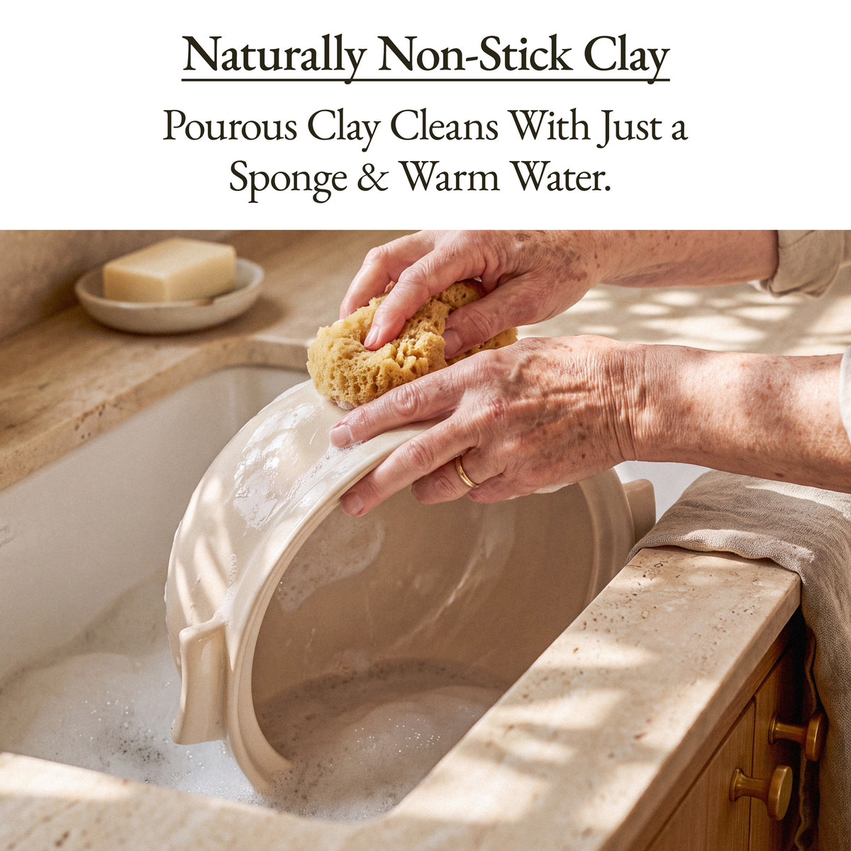 Hands washing the Oatmeal Flami Pot with a sponge and warm water in a sink, naturally non-stick clay