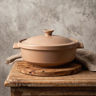 The Flami Pot displayed on a wooden cutting board, showcasing its handcrafted non-toxic clay design.