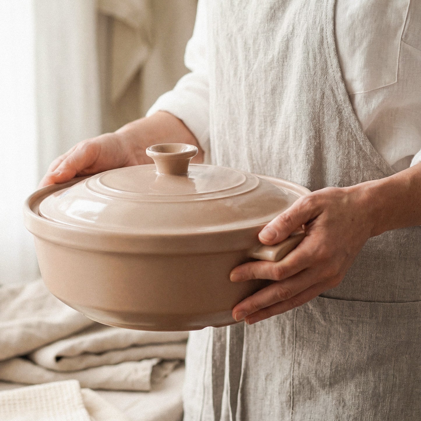 A person holding The Flami Pot, handcrafted non-toxic cookware made from pure clay for toxin-free cooking.