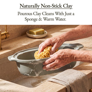 Cleaning a Casserole Claypot Multi-Cooker with a sponge and warm water, showcasing its naturally non-stick clay.